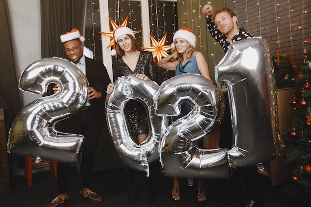 People in a Christman decorations. Man in a black suit. Group celebrations New Year. People with ballons 2021.