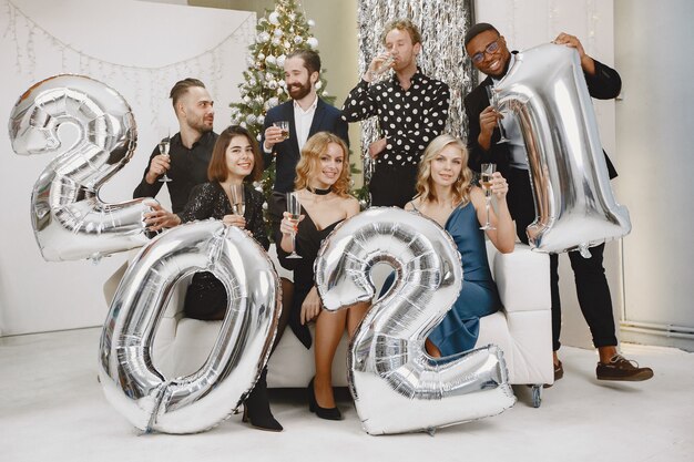 People in a Christman decorations. Man in a black suit. Group celebrations New Year. People with ballons 2021.