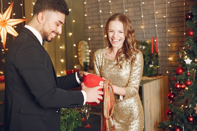 People in a Christman decorations. Man in a black suit. Woman with red box.