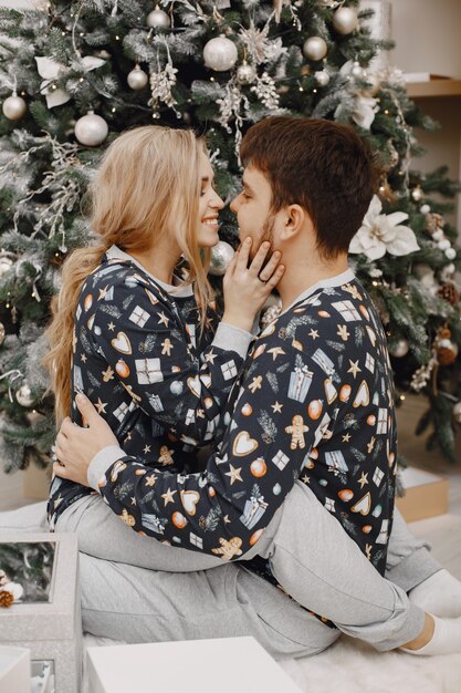 People in a Christman decorations. Man and woman in a identifical pajamas. Family at home.