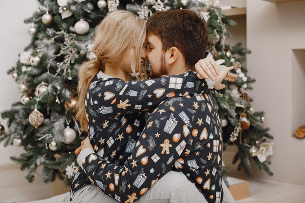 People in a Christman decorations. Man and woman in a identifical pajamas. Family at home.