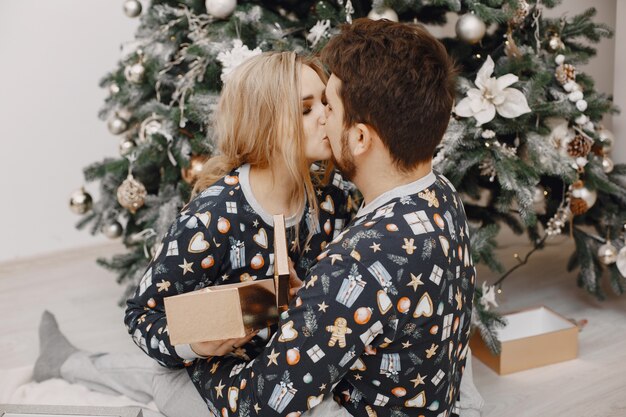 People in a Christman decorations. Man and woman in a identifical pajamas. Family at home.