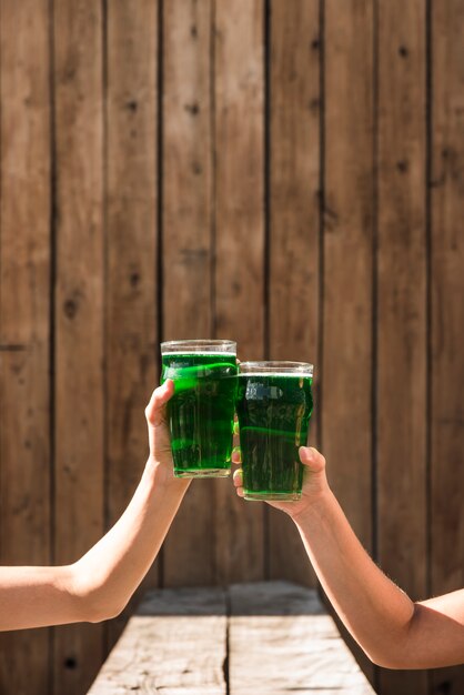 People clanging glasses of green drink near table