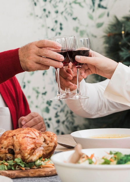People clanging glasses of wine at festive table 
