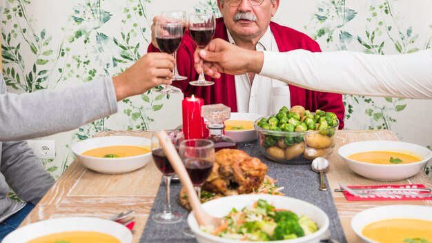 People clanging wine glasses at festive table