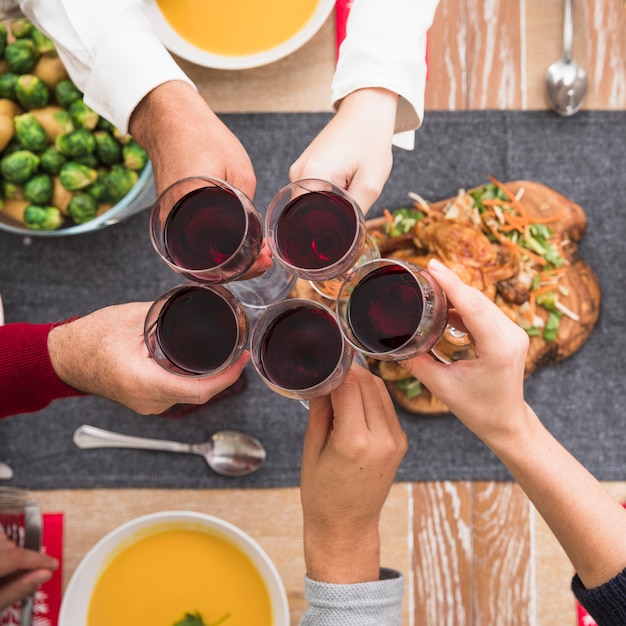 People clanging wine glasses above festive table