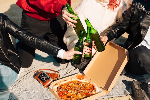 Foto gratuita la gente tintinnio bottiglie di birra sul picnic