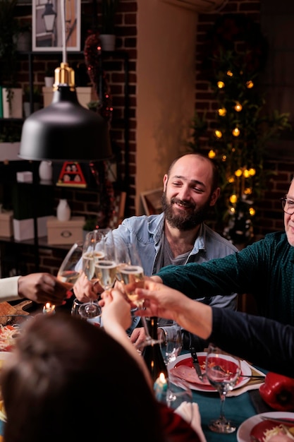 無料写真 スパークリングワインでグラスをチリンと鳴らし、お祝いのディナーでクリスマスの乾杯を提案する人々。両親との冬休みのお祝い、家族の集まり、新年会での飲み会
