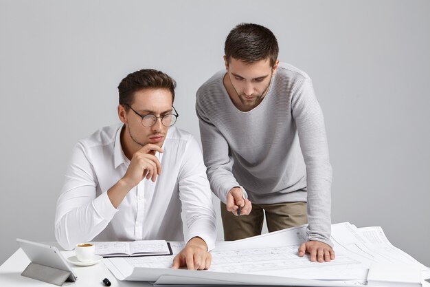 People, collaboration and discussion concept. Professional architect coworkers look attentively at blueprint