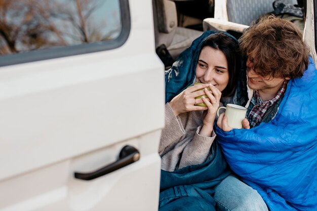 People drinking coffee from their van