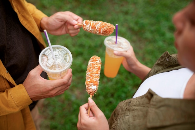 Foto gratuita la gente mangia l'angolo alto del corn dog