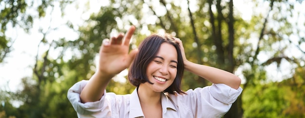 Free photo people and emotions concept happy asian woman laughing and smiling posing on summer day in park