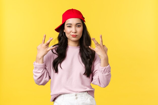 People emotions, lifestyle leisure and beauty concept. Stylish and cute hip-hop dancer girl, showing swag gesture and smirk sassy, acting confident and cool, standing yellow background