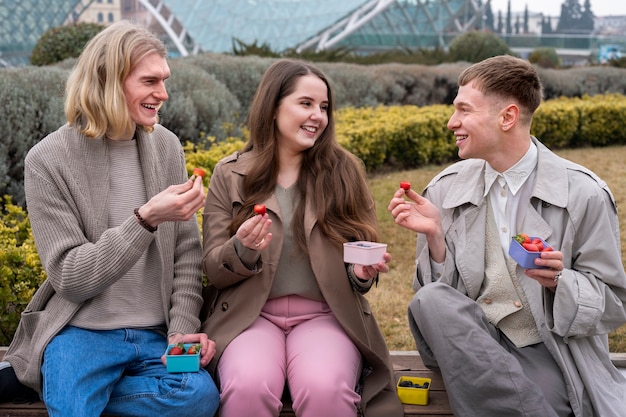 Foto gratuita le persone che si godono uno spuntino di bacche all'aperto