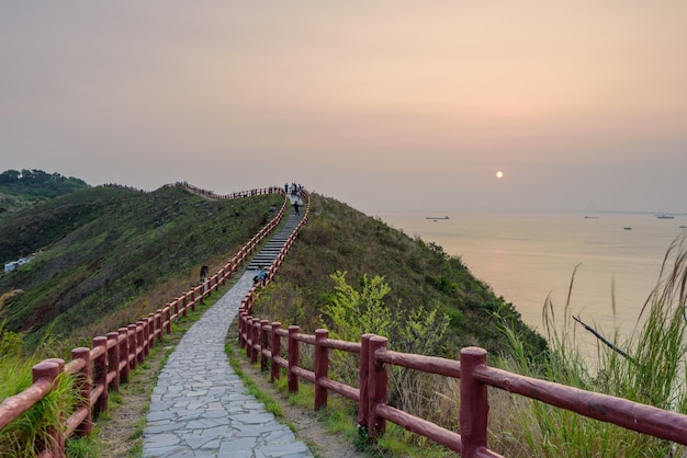 일몰 동안 빨간 울타리가 있는 좁은 길을 지나는 사람들