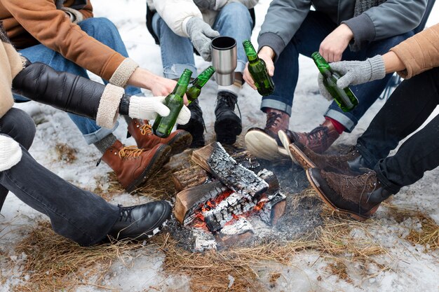 People holding beer bottles by the fire