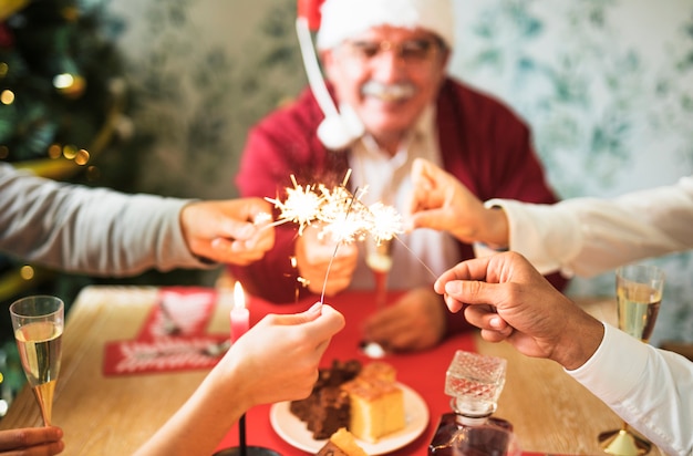 Foto gratuita la gente che tiene i fuochi brucianti del bengala alla tavola festiva