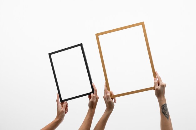 People holding dark and wooden frames