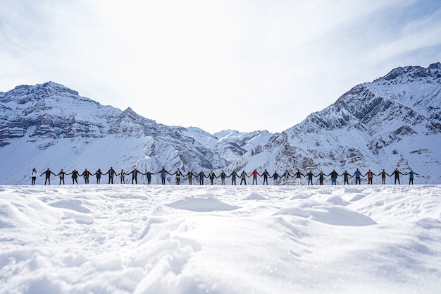 Foto gratuita persone che si tengono per mano in segno di pace con le montagne sullo sfondo in inverno