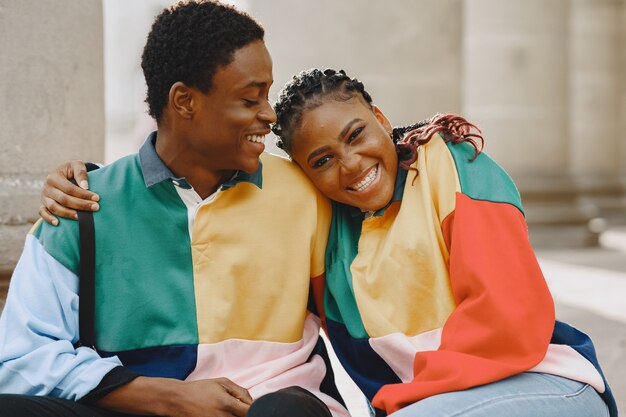 People in identifical clothes. African couple in autumn city. People sitting on a street.