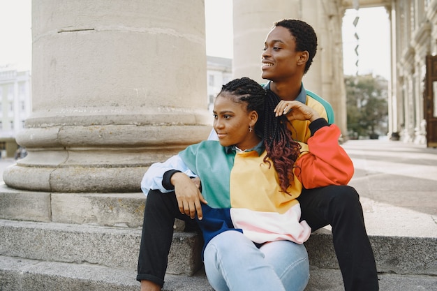 People in identifical clothes. African couple in autumn city. People sitting on a street.