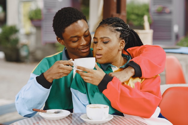 People in identifical clothes. African couple in autumn city. People at the table.