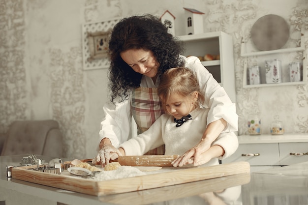 부엌에있는 사람들. 작은 딸과 함께 할머니입니다. 성인 여자는 요리하는 어린 소녀를 가르칩니다.