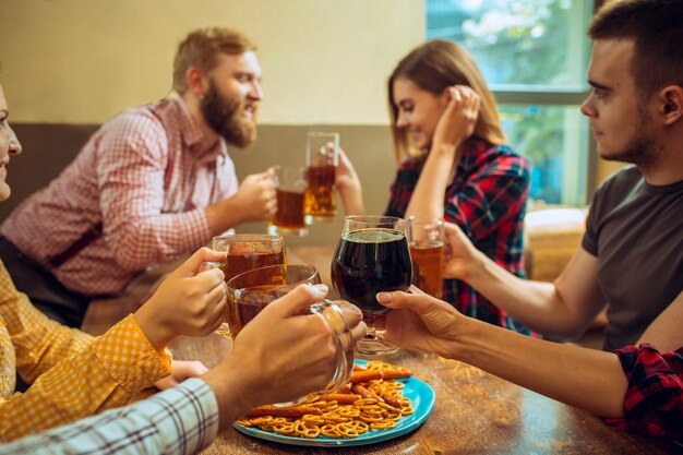 people, leisure, friendship and communication concept. happy friends drinking beer, talking and clinking glasses at bar or pub and making selfie photo by mobile phone.