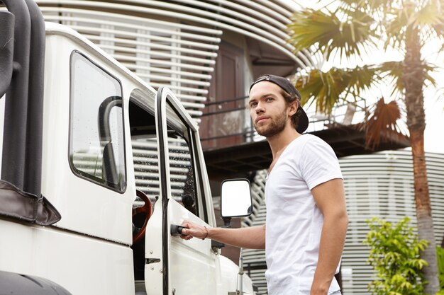 People, leisure and lifestyle concept. Fashionable young male model wearing T-shirt and baseball cap backwards posing outdoors