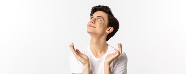 People lgbtq and beauty concept closeup of handsome androgynous man with glitter on face and polishe