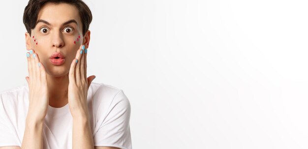 People lgbtq and beauty concept Closeup of handsome gay man express surprise showing hands with blue nail polish standing over white background