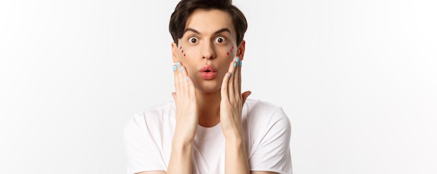 People lgbtq and beauty concept Closeup of handsome gay man express surprise showing hands with blue nail polish standing over white background