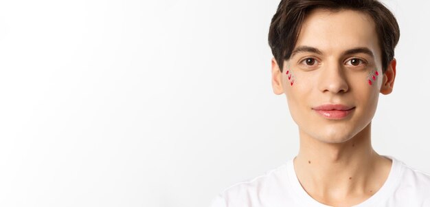 People lgbtq and beauty concept closeup of happy queer guy with applied lip gloss and glitter smilin