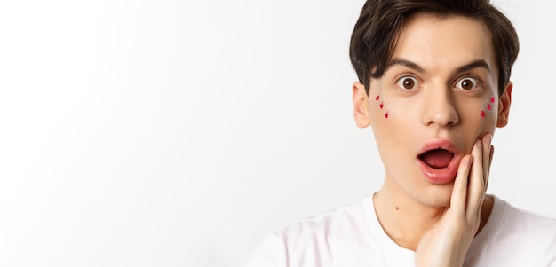 People lgbtq and beauty concept Headshot of handsome gay man looking surprised at camera open mouth wondered standing over white background