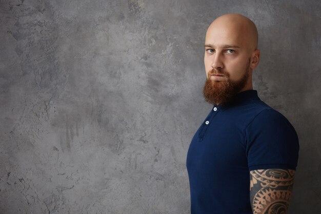 People and lifestyle concept. Waist up image of attractive fashionable young European unshaven male with bald head and stylish ginger beard having bad day,