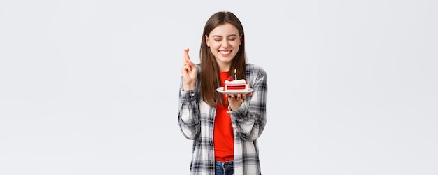 人々のライフスタイルの休日とお祝いの感情の概念誕生日ケーキに願い事をするためにろうそくを吹くように目を閉じて祝う幸せな陽気なbday女の子は指を交差させます