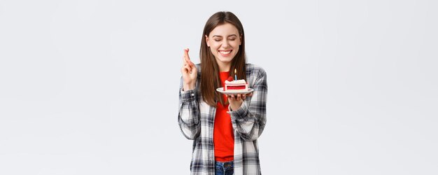 People lifestyle holidays and celebration emotions concept Happy cheerful bday girl celebrating close eyes cross fingers as blowing candle to make wish on birthday cake