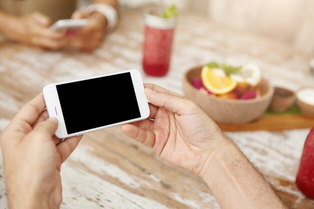 People, lifestyle and modern technology concept. Close up shot of man's hands with generic smart phone