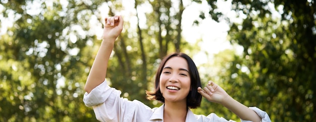 People lifestyle portrait of young brunette woman dancing smiling and laughing walking in park with