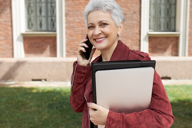 Persone, stile di vita, tecnologia e concetto di comunicazione. ritratto di signora allegra alla moda di mezza età di affari che parla sul cellulare