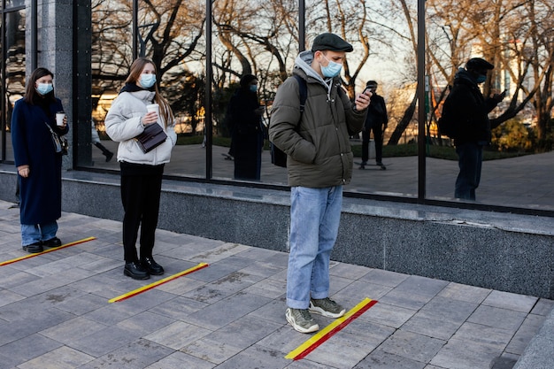 People in line waiting behind social distance stripe