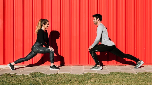 People lunging near red wall