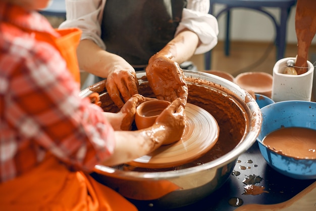Люди, делающие вазу из глины на гончарном станке