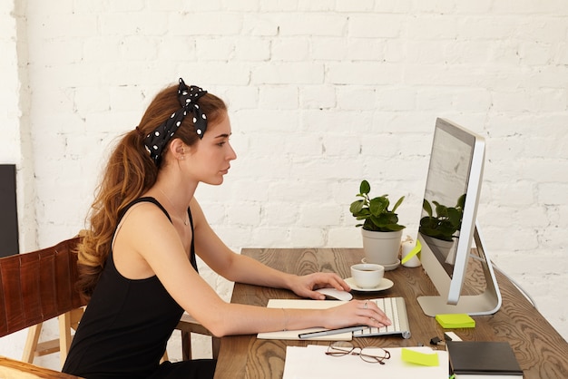 Free photo people, modern technology, job, occupation,profession, business and education concept. serious concentrated businesswoman working from home, sitting at her workplace and keyboarding on computer