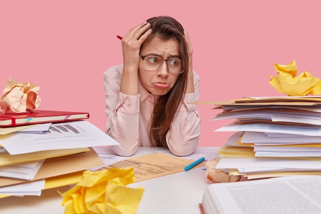 Foto gratuita persone, sentimenti negativi e concetto di depressione. studente dispiaciuto o sovraccarico di lavoro tiene le mani sulla testa, ha l'emicrania dopo aver fatto gli straordinari