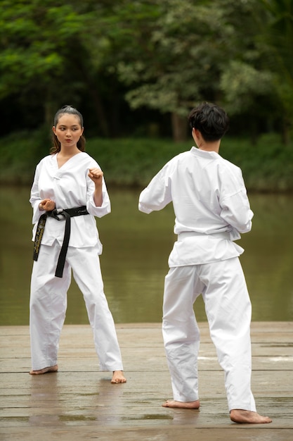 Free photo people outdoors in nature training for taekwondo