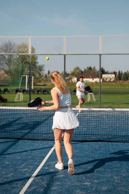 Люди играют в паддл-теннис на открытом воздухе в полный рост