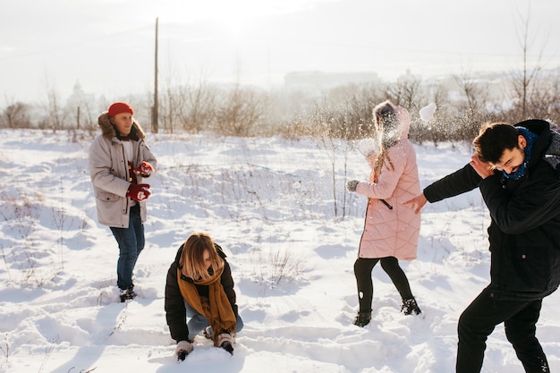 People playing snowballs in winter forest 