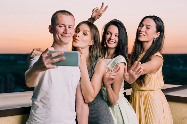 People posing for selfie on rooftop at dawn