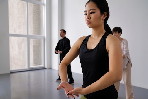 Persone che praticano il tai chi al chiuso vista laterale